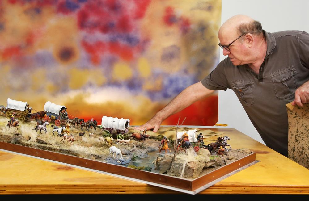white man leaning over a diorama