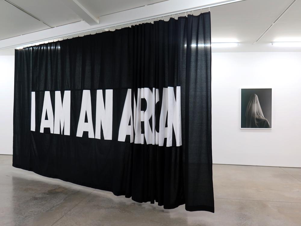 A large black fabric banner with white type face that says I am an and the last word is not clearly written out