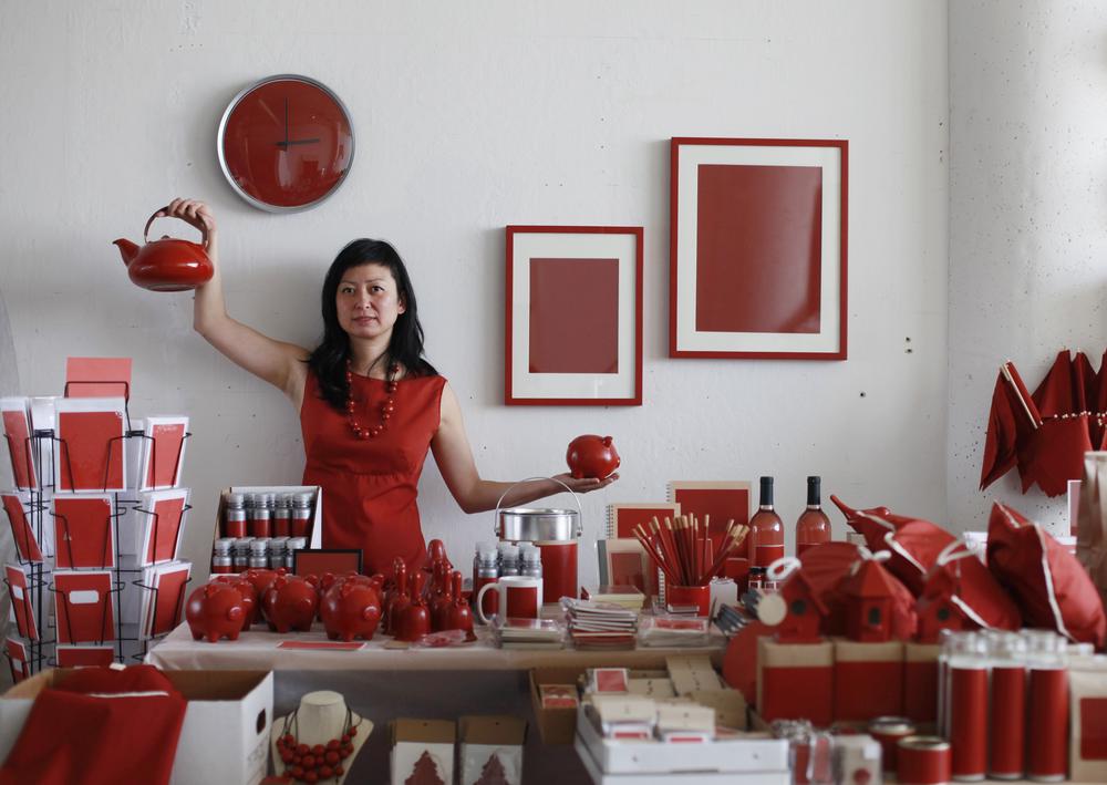 artist holding products from her red colored store and collateral