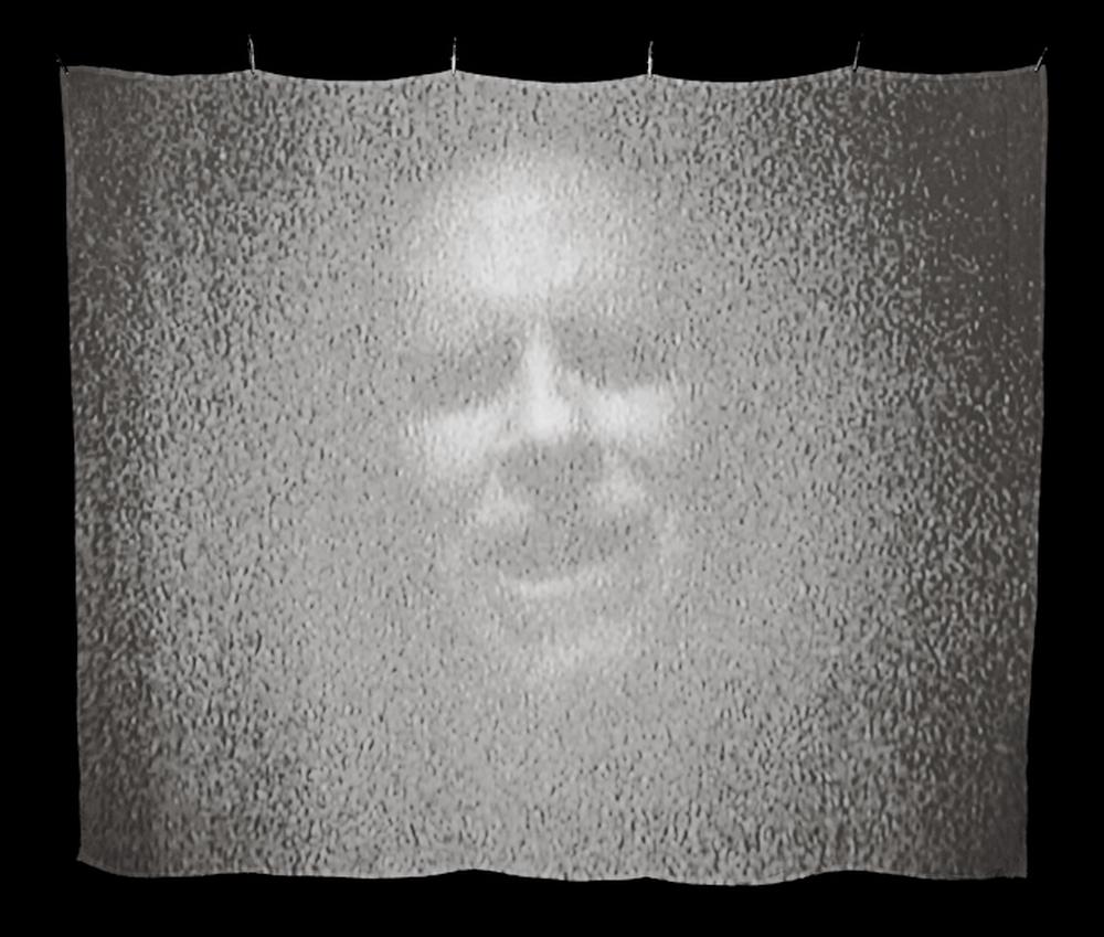 ghostlike image of a face projected on a silk screen