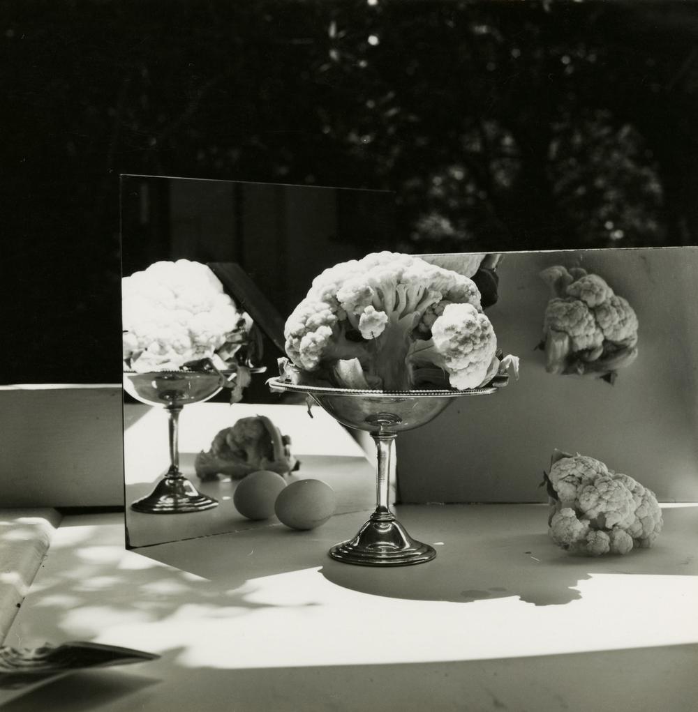 cauliflower in a silver vase is refelcted off mirrors placed behind to the left and right at angles towards the viewer