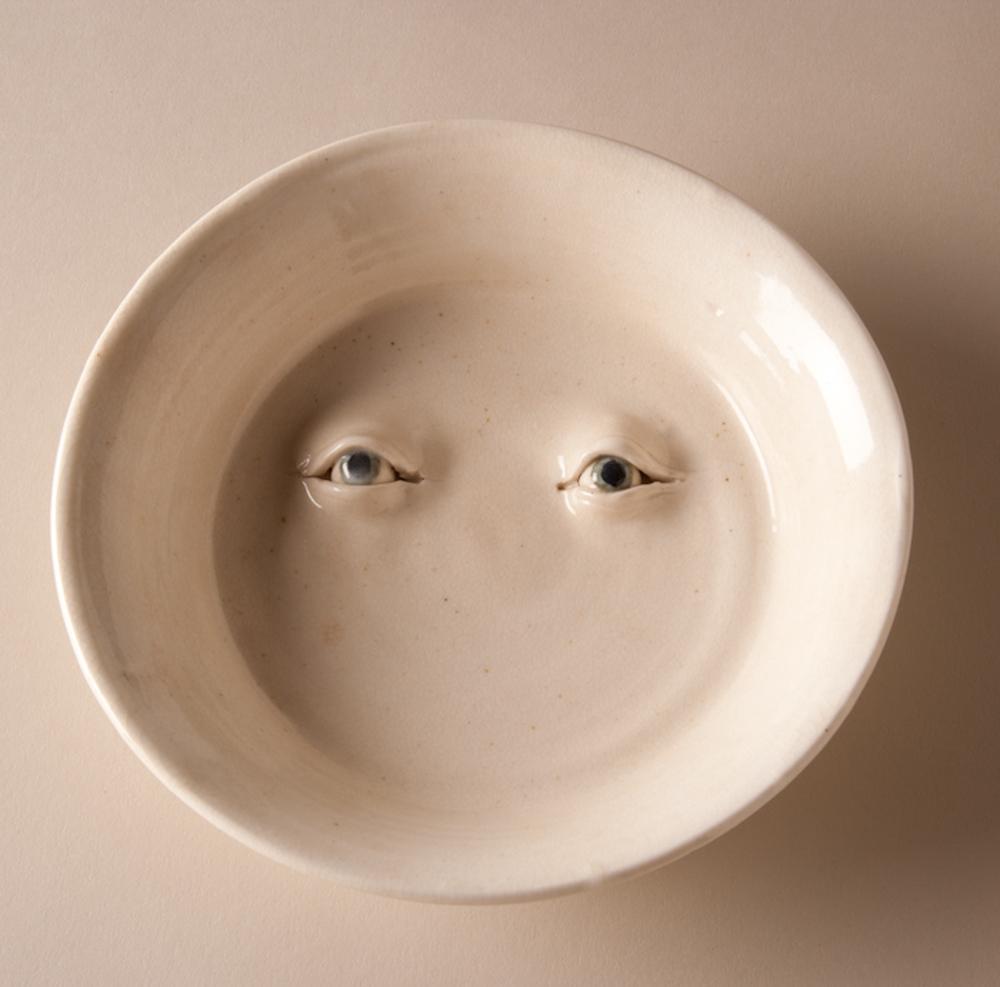 ceramic dish with two eyes sculpted into the bottom of the bowl