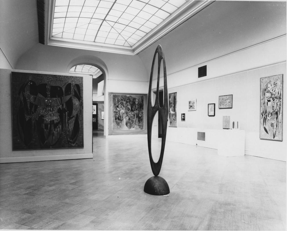 veiw of gallery with arched skylight and a mix of sculptures and paintings