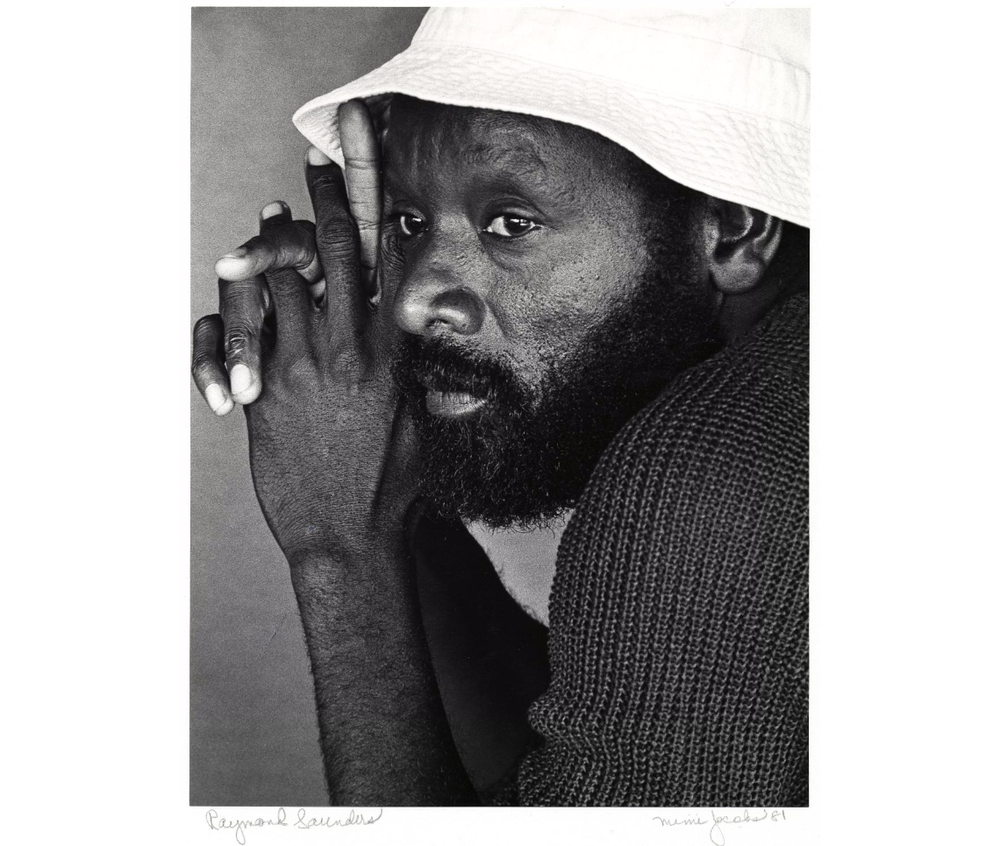 black and while profile image of a black man with hands clasped together wearing a dark sweater and white bucket hat
