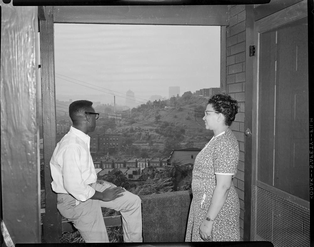 A man and woman looking out of a window at the city landscape