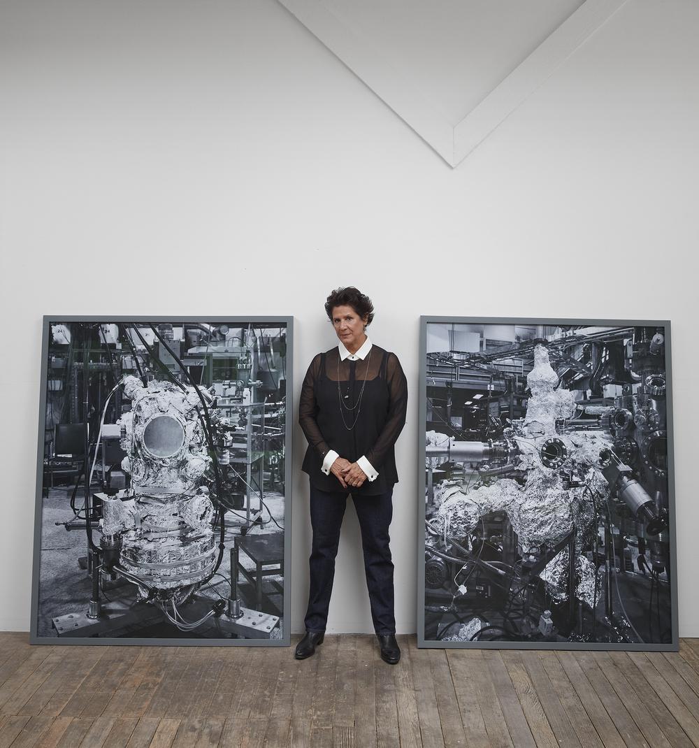 artist standing in between two framed pieces of her work